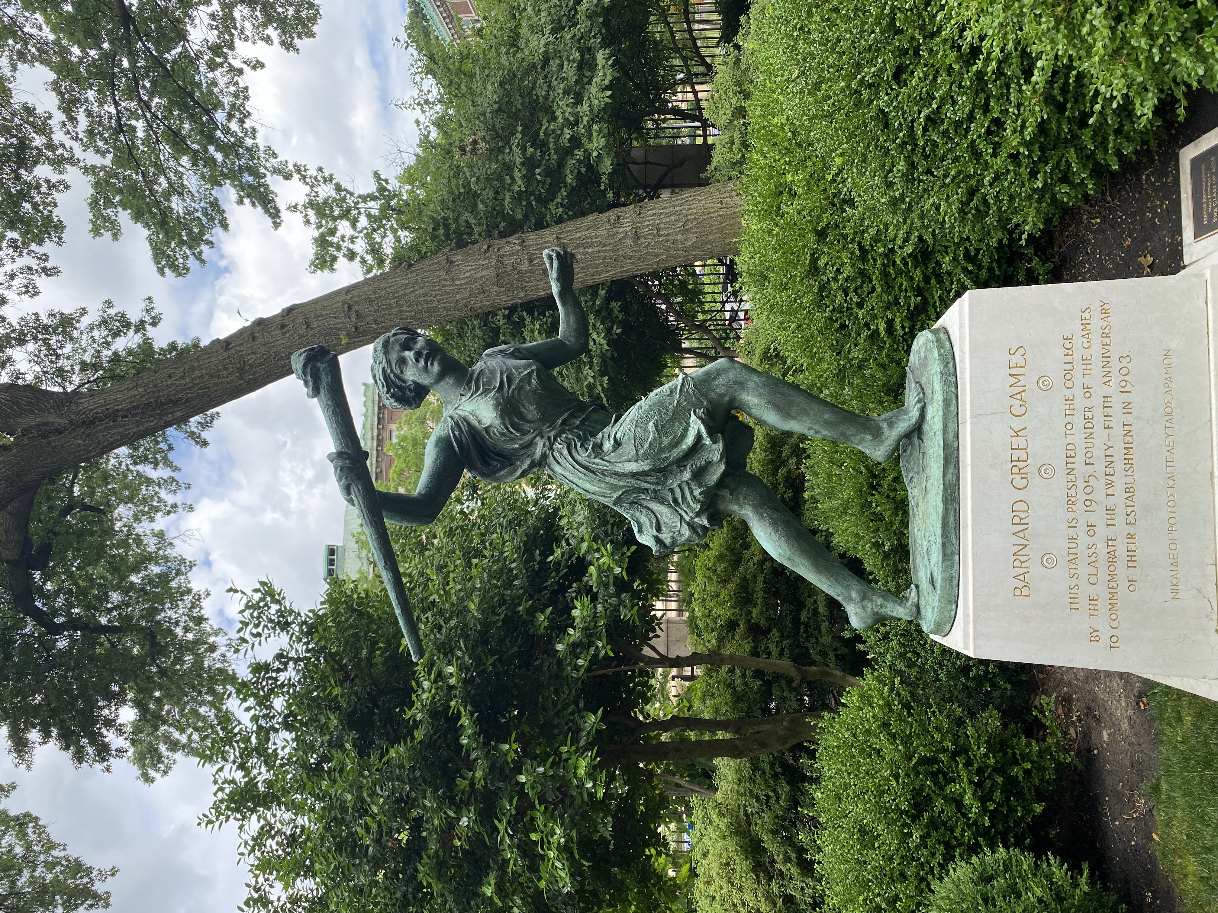 Head on shot of Greek Games statue and base with greenery in the background